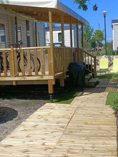 a wooden deck with a gazebo in front of a house at mobil-home neuf 4-6 places camping Siblu les viviers in Lège-Cap-Ferret