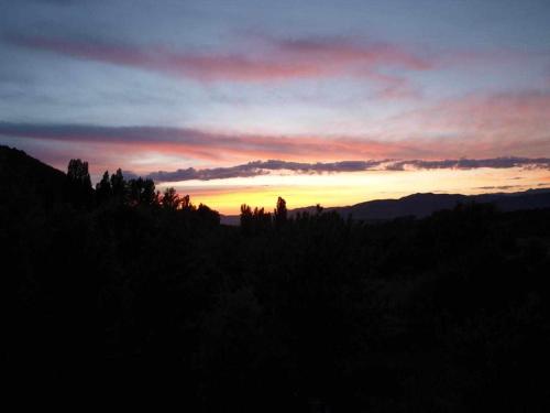 a sunset in the sky with trees and mountains at Casapirineos Apartamentos in Ulle