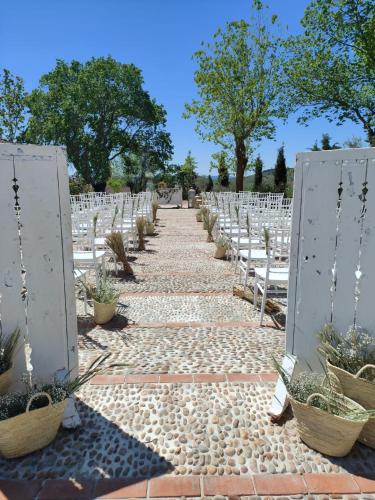 an aisle with white chairs and potted plants at Hotel El Coto De Quevedo in Torre de Juan Abad