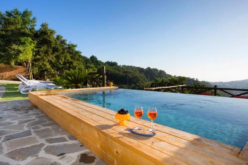 - deux verres de vin assis sur une table en bois à côté de la piscine dans l'établissement I Giardini di Sorrento, à Sorrente