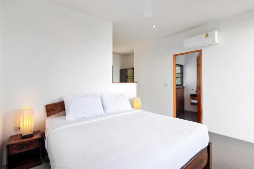 a white bedroom with a white bed and a mirror at 2 Bays Villa in Thong Nai Pan Yai