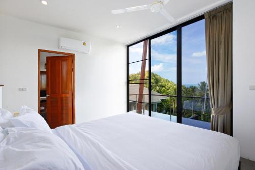 a bedroom with a white bed and a large window at 2 Bays Villa in Thong Nai Pan Yai