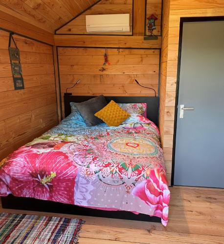 a bedroom with a bed in a wooden cabin at Hoogte Huisje Fantasie in Swalmen