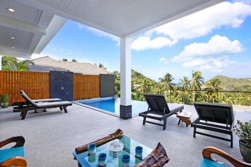a patio with chairs and a table and a pool at 2 Bays Villa in Thong Nai Pan Yai