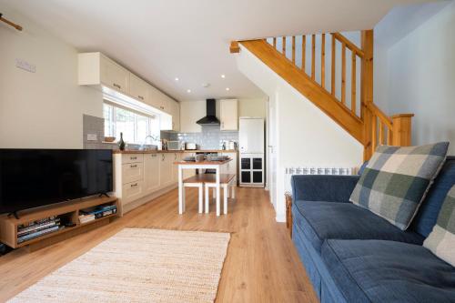 a living room with a blue couch and a kitchen at Owlet Lodge in Chislet