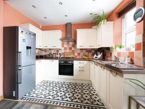 a kitchen with white cabinets and a black refrigerator at Comfortable Bristol Escape near Gloucester Road in Bristol