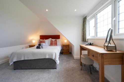 Schlafzimmer mit einem Bett, einem Schreibtisch und Fenstern in der Unterkunft Owlet Lodge in Chislet
