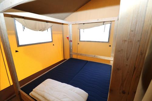 a small room with a blue bed and two windows at De Zuidvliet Glamping Deluxe 2 in Wolphaartsdijk