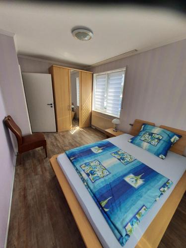 a bedroom with a large bed with a blue blanket at Ferienwohnung 24 Unten Rechts 3 Zimmer in Lathen