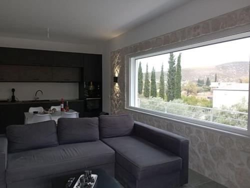 a living room with a couch and a large window at Serenity - Brand new apartment in Ermioni Village in Ermioni