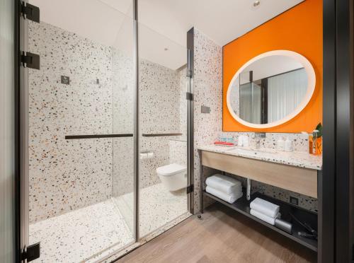 a bathroom with a shower and a toilet and a mirror at EVEN Hotels Shenzhen Guangming Cloud Park, an IHG Hotel in Shenzhen