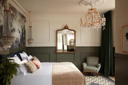 a bedroom with a bed and a mirror and a chandelier at Château Léognan, Domaine viticole - proche Bordeaux in Léognan