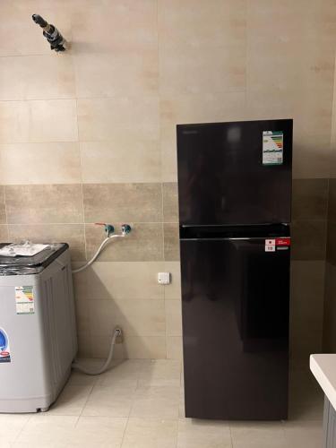 a black refrigerator in a kitchen with a wall at اطلالة الريان شقة خاصة in Jeddah