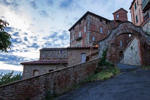 a large brick building with an archway next to a wall at Semidetached Villa Shared Pool - Happy Rentals in Colle