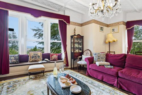 a living room with purple furniture and windows at The Round House - Panoramic views of Devon's Coast and Country in Ilfracombe