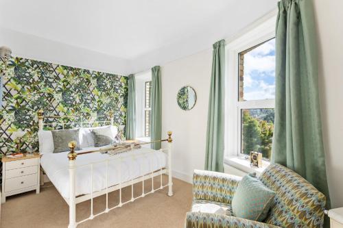 a bedroom with a bed and a chair and a window at The Round House - Panoramic views of Devon's Coast and Country in Ilfracombe