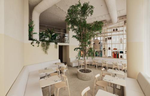 un restaurant avec des tables blanches, des chaises et des plantes dans l'établissement Enso District Hotel, à Knokke-Heist