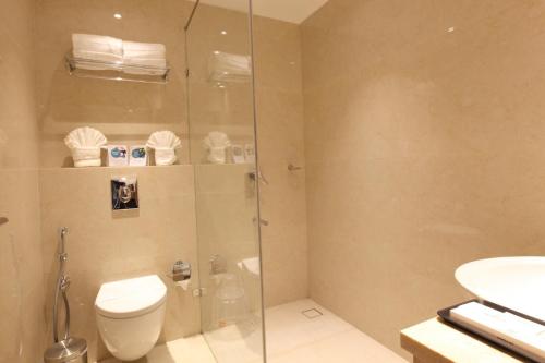 a bathroom with a toilet and a glass shower at THE GRAND AMBASSADOR HOTEL in Kottayam