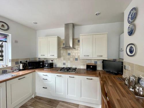 a kitchen with white cabinets and a stove top oven at Elim in Dartmouth with stunning River Dart view in Dartmouth