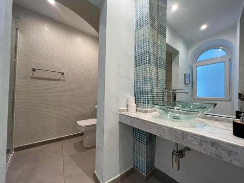 a bathroom with a glass sink and a toilet at 2BR 2BA with private patio your serene escape in Gibraltar