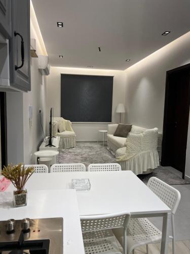 اطلالة الريان شقة خاصة في جدة: غرفة معيشة بطاولات بيضاء وكراسي وشاشة