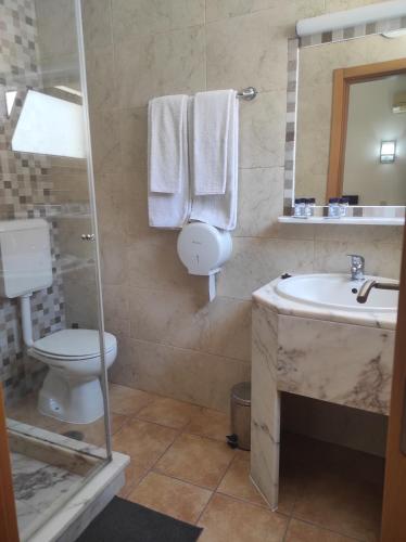 a bathroom with a sink and a toilet and a mirror at Hotel Bela Vista in Olhão