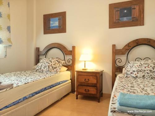 a bedroom with two twin beds and a night stand at Apartamentos StarNerja II in Nerja