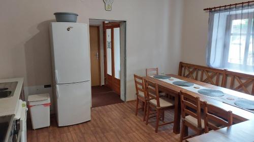 a kitchen with a table and a white refrigerator at Chalupa a apartmány Marika in Cerny Dul
