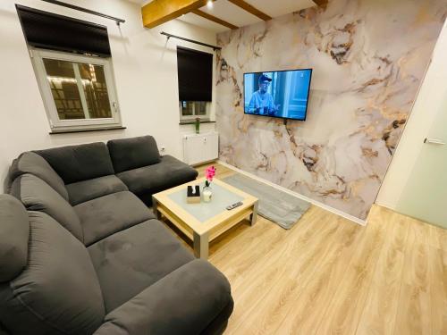 uma sala de estar com um sofá e uma televisão na parede em Elegante Wohnung mit Charme am Marktplatz - 3Z - nähe Frankfurt am Main & Hanau em Nidderau