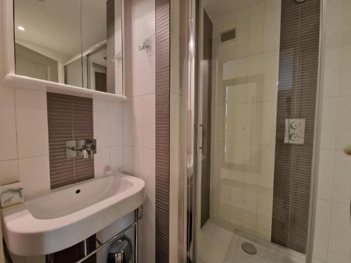 ein weißes Bad mit einem Waschbecken und einer Dusche in der Unterkunft Comfortable in Cannes in Cannes