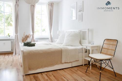 um quarto branco com uma cama e uma cadeira em Stilvolles Apartment im Zentrum em Magdeburg