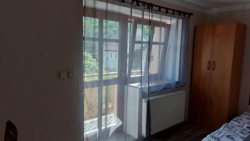 a room with a large window with blue curtains at Chalupa a apartmány Marika in Cerny Dul