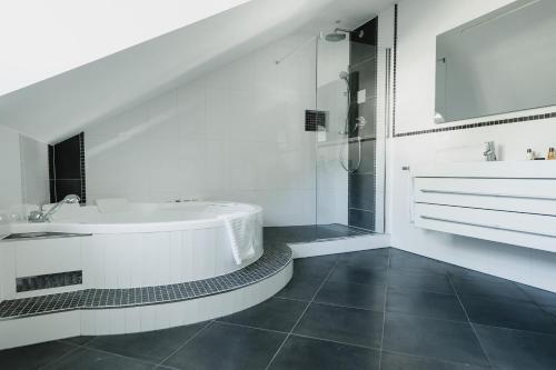 a white bathroom with a tub and a shower at City Chalets Salzburg in Salzburg