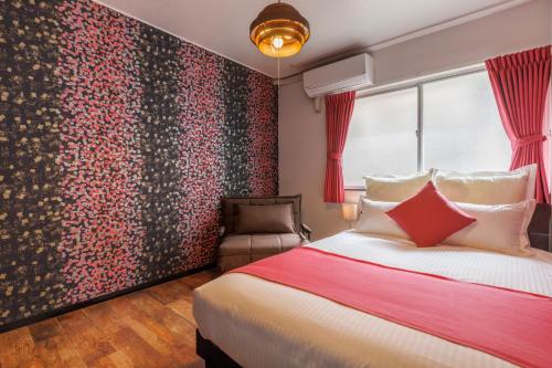 a bedroom with a bed and a red wall at Residential Hotel Naha Miebashi in Tomari