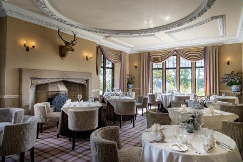a dining room with tables and chairs and a fireplace at Kincraig Castle Hotel in Invergordon