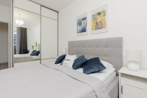 een slaapkamer met een groot wit bed met blauwe kussens bij Cozy Apartment with Parking Bakalarska by Renters in Warschau