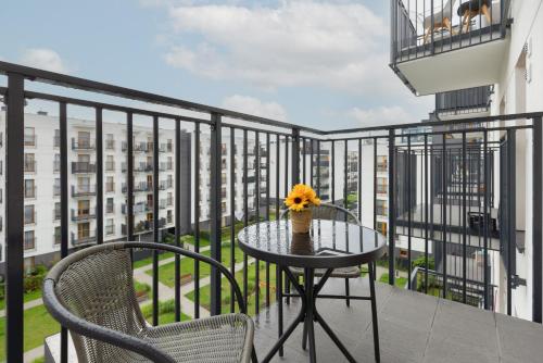 a table and two chairs on a balcony with a view at Cozy Apartment with Parking Bakalarska by Renters in Warsaw