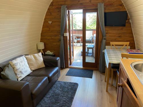 a living room with a couch and a table and a kitchen at Acorns Luxury Glamping in Holywell