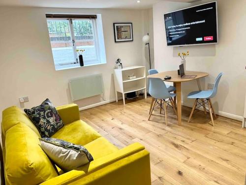 a living room with a yellow couch and a table at Forbury Apartment, 3 guests, Free Parking & Wifi, close to Uni, Hospital & Town Centre in Reading