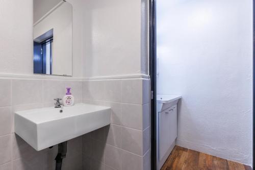 a white bathroom with a sink and a mirror at Residential Hotel Naha Miebashi in Tomari