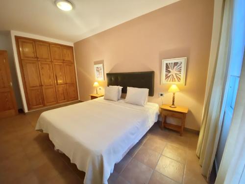 a bedroom with a large white bed and two lamps at Casa Cecilia in Playa de San Juan