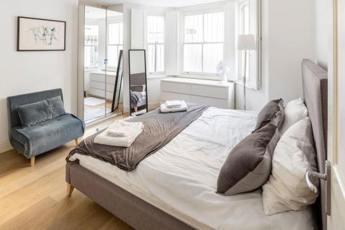 een slaapkamer met een groot bed en een stoel bij Superior 5* Kensington, London Flat + Free Wi-Fi in Londen
