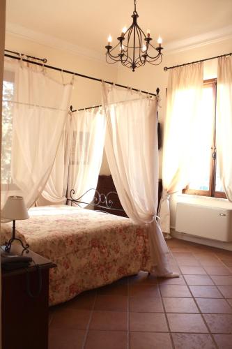 a bedroom with a bed with white curtains and a chandelier at Residenza Porta Guelfa in Bevagna