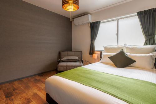 a bedroom with a large bed and a chair at Residential Hotel Naha Miebashi in Tomari