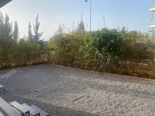 a gravel parking lot with a fence and trees at Prestigia 3 Bedrooms with swimming pool in Rabat