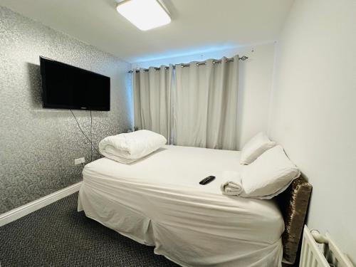 ボルトンにあるUNIQUE PRIVATE ROOMSのベッド1台、壁掛けテレビが備わるホテルルームです。