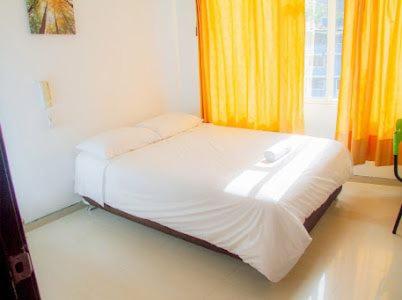 a white bed in a room with yellow curtains at Hotel El Palacio Del Rey in Duitama