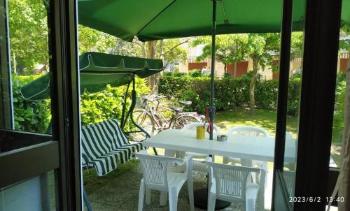 uma mesa branca e cadeiras com um guarda-sol verde em Residence Pineda A 6 em Bibione