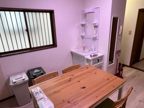 ein Esszimmer mit einem Holztisch und einem Waschbecken in der Unterkunft Sepia Court Inn セピアコートイン in Urayasu