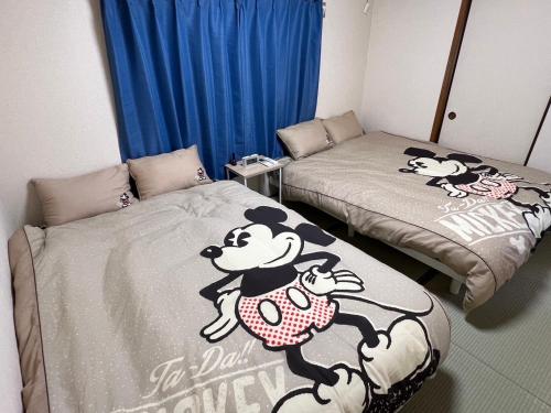 a room with two beds with winnie the pooh beds at Sepia Court Inn セピアコートイン in Urayasu
